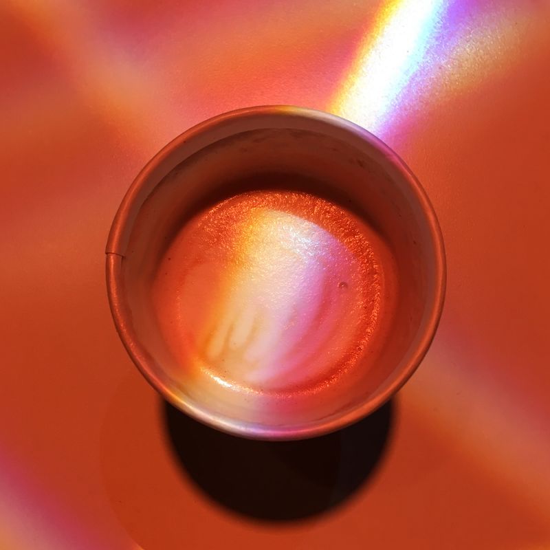 a cup of coffee, lit up by colorful light