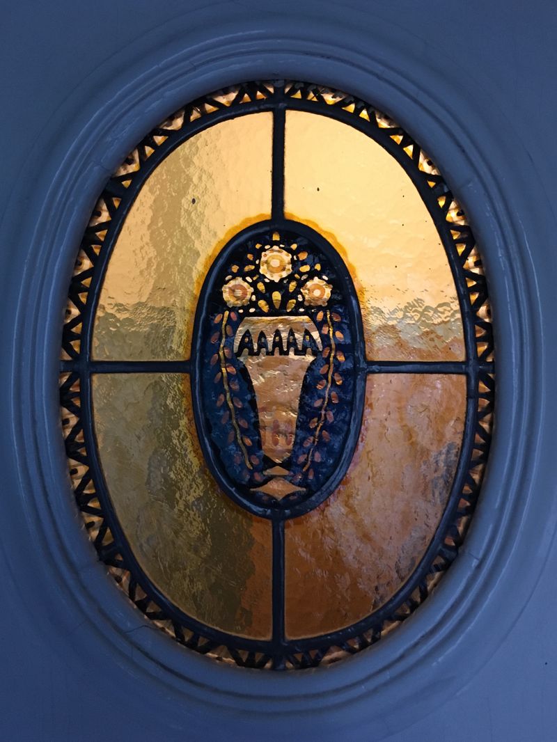 golden light gleaming through a decorated window in a blue-ish door