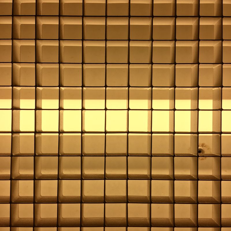 yellow neon light behind a metal grate