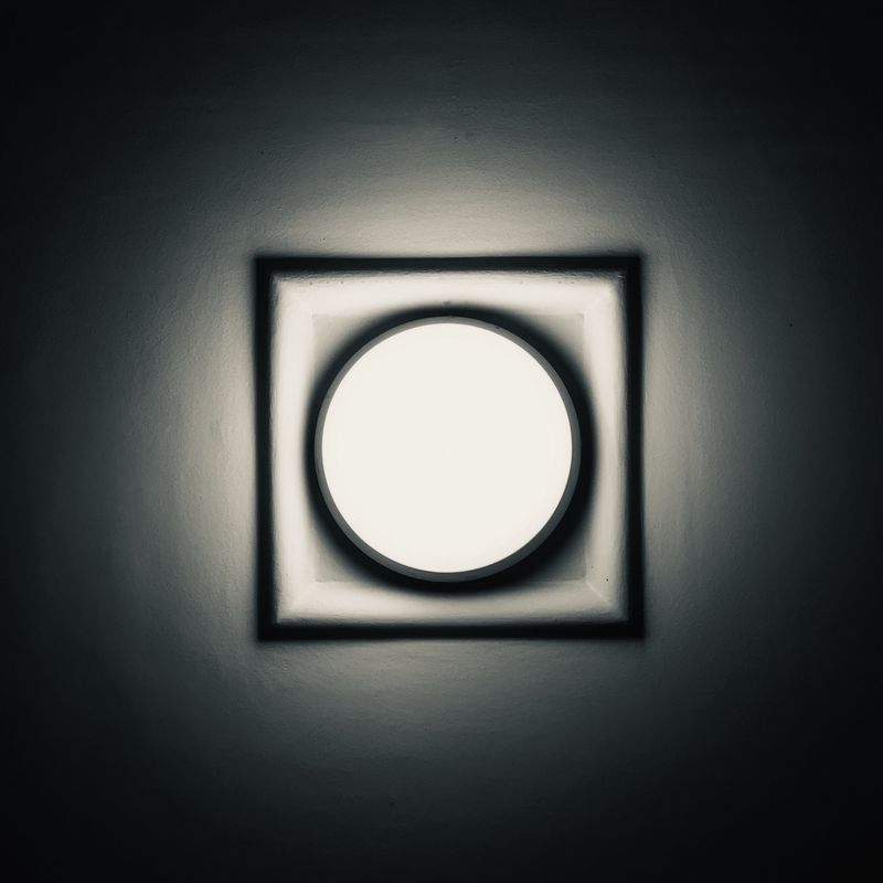 greyscale photo of a lamp illuminating a white surface