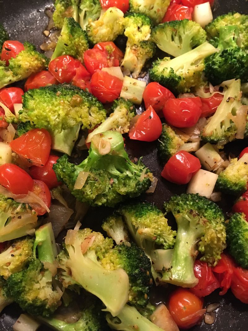 fried tomatoes and broccoli in a pan