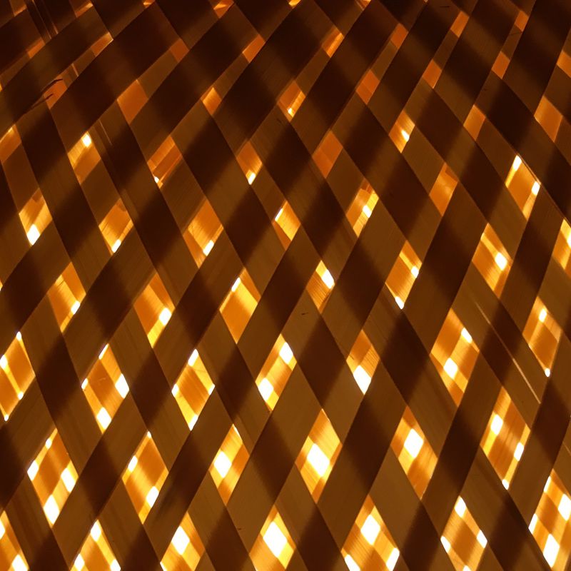 light shining through a geometric pattern of overlapping bamboo strips